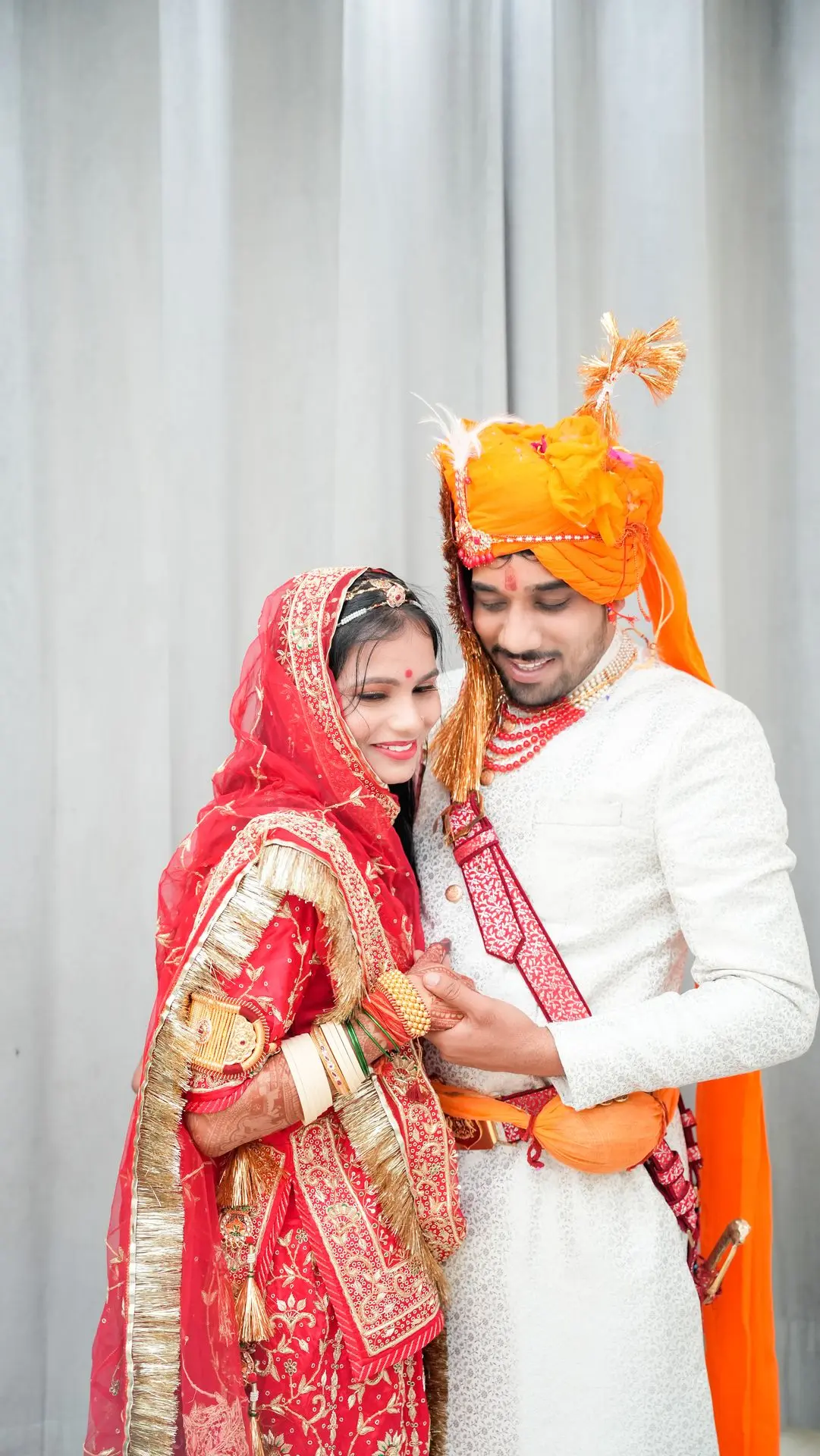 Close-up portrait of a smiling bride in red lehenga and bridal jewelry.
