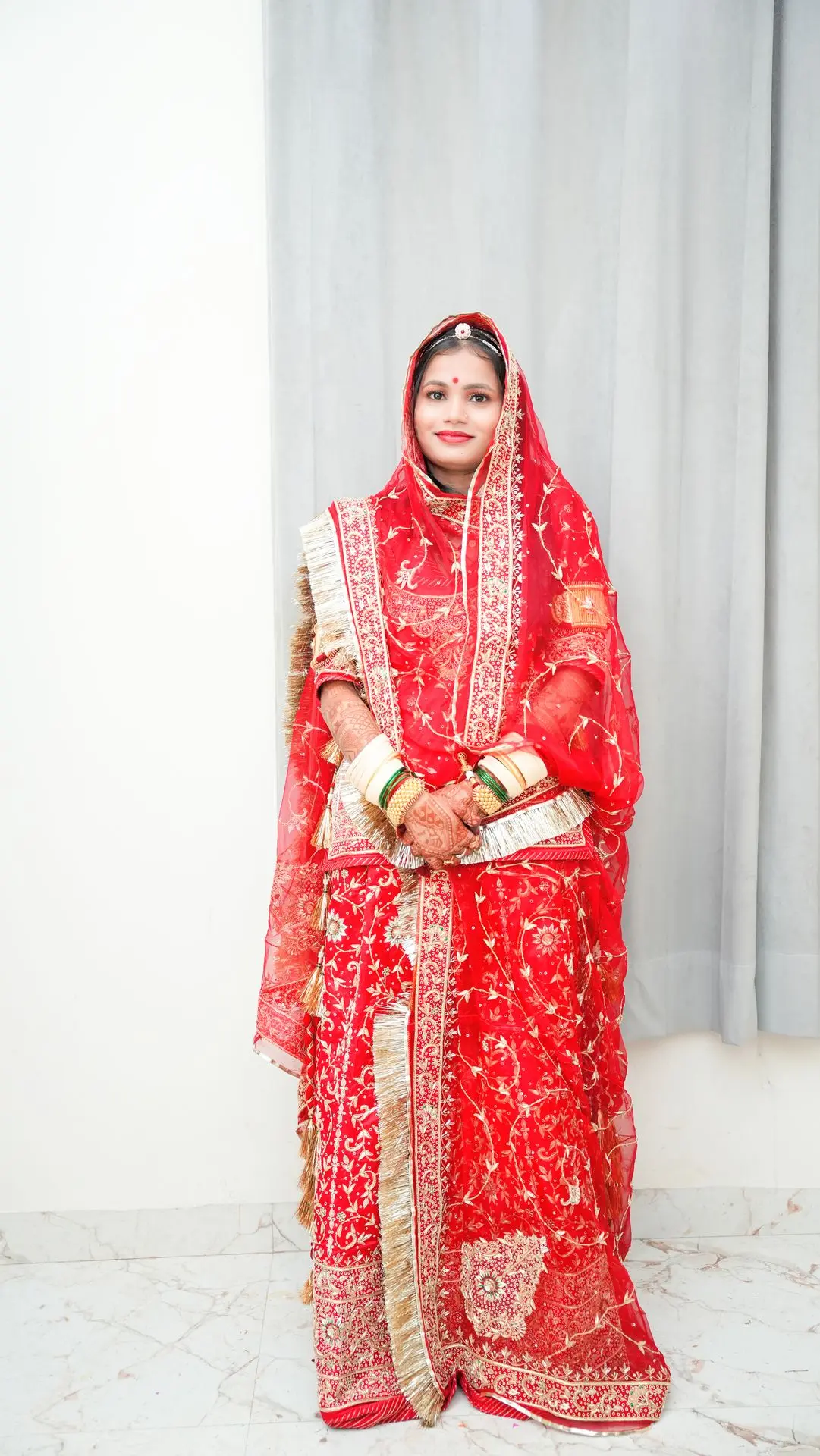 Bride holding floral garland during Indian wedding ceremony.