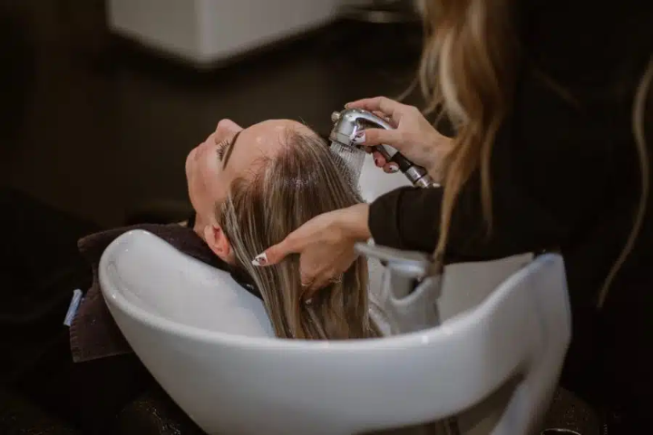 Hair stylist washing and prepping a client’s hair at the salon sink before treatment at Bright Luxe Salon &amp; Studio.