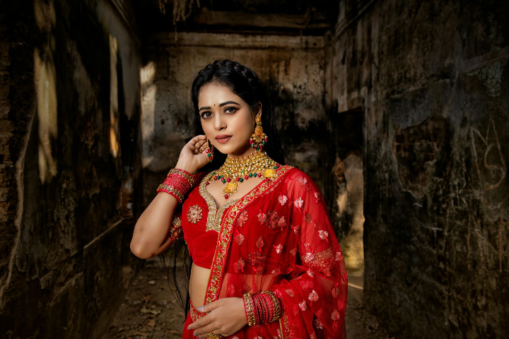 Bride dressed in traditional red wedding attire posing for a photoshoot at Bright Luxe Salon &amp; Studio.